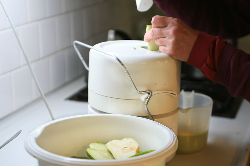 Iemand haalt de sap uit de appels met een machine